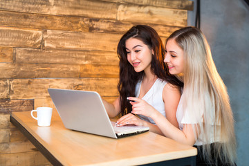two beautiful young woman at a table with a laptop