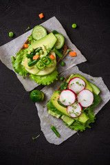 Vegetarian toast with salad, vegetables and fruits, healthy Breakfast on black concrete background