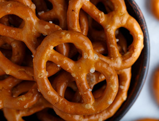 Mini pretzels with salt in a ceramic bowl close-up. Beer appetizer on a gray background. Selective focus, top view