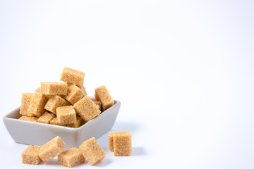 Brown sugar in a square cup on a white background, healthy sugar is used for cooking or desserts.