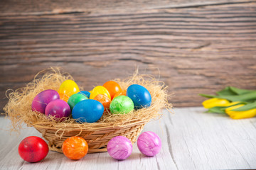 Fototapeta na wymiar Beautiful group Easter eggs in the spring of easter day, red eggs, blue, purple and yellow in Wooden basket on the table background wood