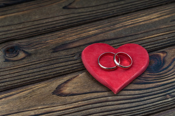 Wedding rings on a red heart, on a wooden table background