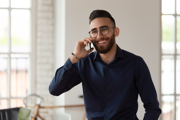 Millennial middle eastern ethnicity businessman talking on phone in office