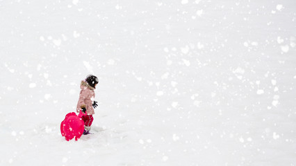 A little girl walking on the snow with her family are enjoying a winter snowy vacation and doing...