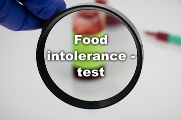 A blood sample for a test for food intolerance. The doctor’s hand holds a magnifying glass in...