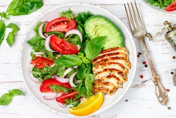 Salad with fried chicken breast, lettuce, tomatoes, red onion, avocado, lemon, olive oil and Basil. Caesar. Delicious and healthy dinner for gourmets. Selective focus