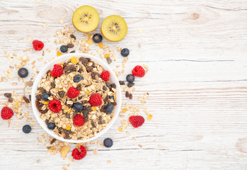 Breakfast Served in the morning with corn flakes Whole grains and raisins with milk in cups and Strawberry, Blueberry, Raspberry, Kiwi on the wood table,Diet food or healthy food in the morning.
