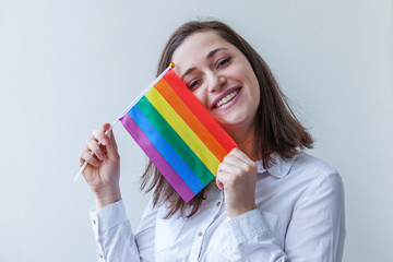 Beautiful caucasian lesbian girl with LGBT rainbow flag isolated on white background looking happy and excited. Young woman Gay Pride portrait. Equal rights for lgbtq community concept.