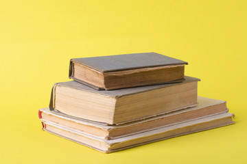 Several old books on a yellow background close-up.