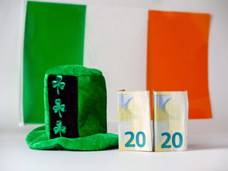 Green hat with shamrock, Irish National flag in the background two euro banknotes folded making 2020 year Saint Patrick day celebration.