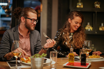 Group of friends sitting in retaurant and eating dinnner.