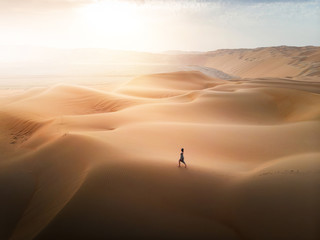 Woman walking on the desert sand dunes aerial view - Powered by Adobe