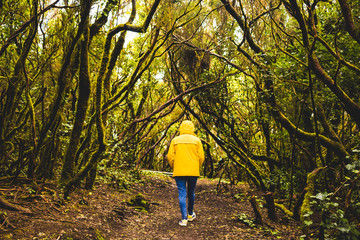 mujer caminando por el bosque con chaqueta amarilla