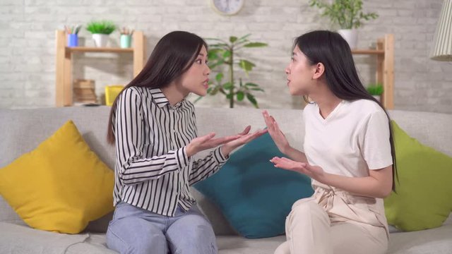 Two young asian women are quarrel and angry at each other sitting in the living room