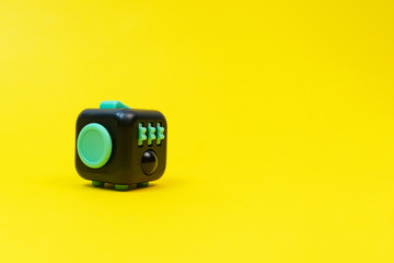 Black and green fidget cube on yellow background, minimal concept, copyspace.  - obrazy, fototapety, plakaty