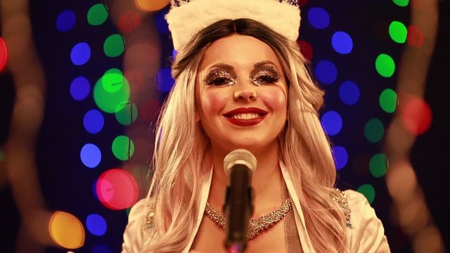 Video clip young woman singer in a New Year costume Snow Maiden sings a song in stage light