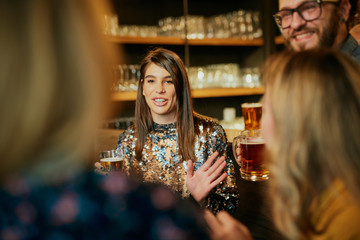 Group of friends drinking beer, chatting and having good time at pub. Night out.