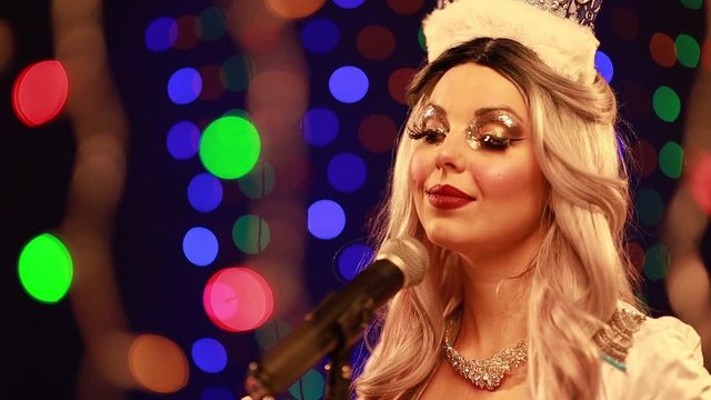 Video clip young woman singer in a New Year costume Snow Maiden sings a song in stage light