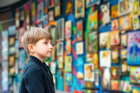A boy in an art gallery examines art.