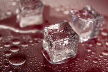 Pyramid of melted ice cubes with drops of water on a red