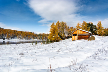 Wooden house in the mountains. Change of seasons. Winter replaces autumn.