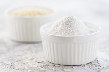 Rice flour in a white bowl on a gray table. Gluten free, healthy diet concept.