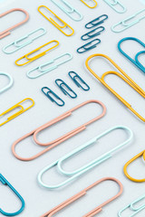 Top view of Colorful paper clips over the  pastel background. Modern abstract concept of working space, studies