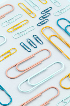Top view of Colorful paper clips over the  pastel background. Modern abstract concept of working space, studies