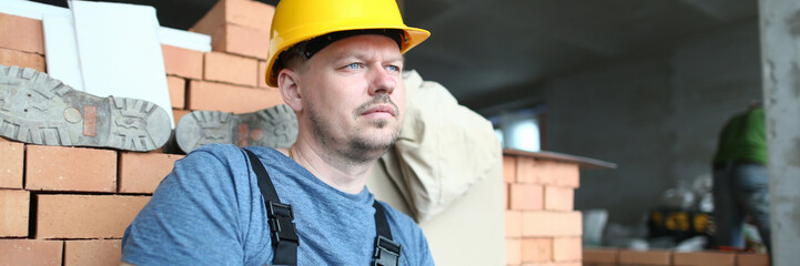 Portrait of concerned man looking away with pensiveness. Constructor holding plan folder and...