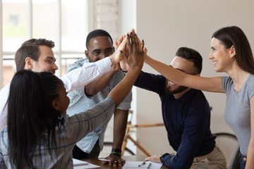 Excited multinational employees celebrating team victory giving high five