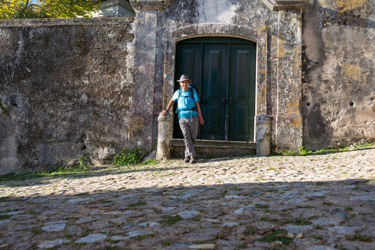 Man In Hat And Blue Shirt Next To A Door