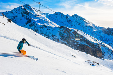Fototapeta na wymiar Skier rides down the slope in Alps mountains. Winter sport. Val Thorens, 3 Valleys, France. Beautiful mountains, winter landscape