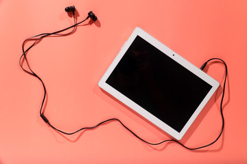 headphones with a white tablet on a pink background