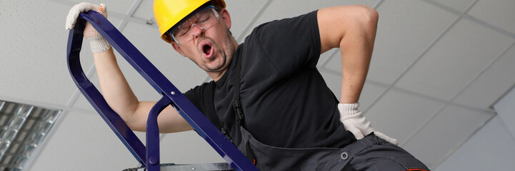 Adult caucasian handyman hold hand on lower back portrait. Occupational Safety and Health concept