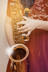 Saxophone in the hands of a girl. Girl with saxophone at a concert_