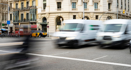 Obraz premium Two white vans moving quickly through the city.