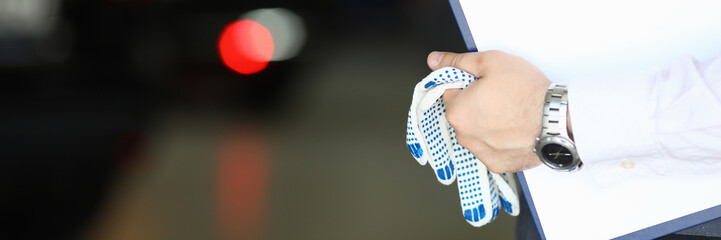 Focus on hands of engineer holding paper folder with technical description about autos and working...