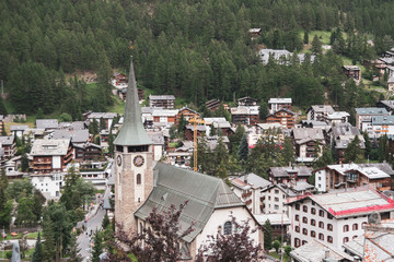 Spectacular view of the mountain village of Zermatt. Coniferous forest on the slopes of the mountains