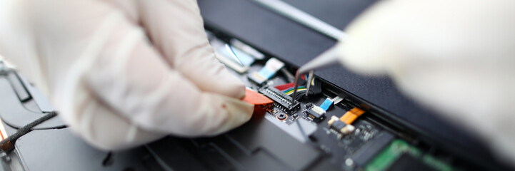 Focus on fixing wires in pc. Technician wearing gloves repairing personal computer using tweezers. Technical support of gadgets and devices restoring productivity of electronics