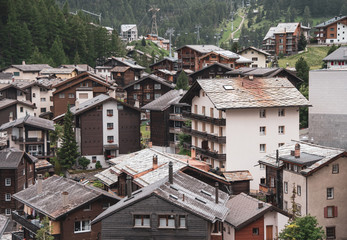 Fototapeta na wymiar View of the roofs of chalets in a Swiss resort. A place preserving authentic architecture. Natural stone roofs, wooden facades. Zermatt, Switzerland.