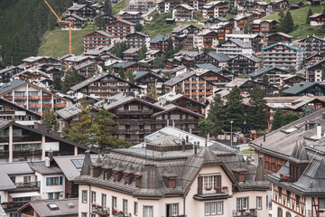 Fototapeta na wymiar View of the roofs of chalets in a Swiss resort. A place preserving authentic architecture. Natural stone roofs, wooden facades. Zermatt, Switzerland.