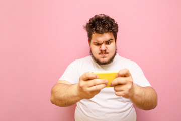 Portrait of an overweight young overweight man playing mobile games on a sad-faced smartphone. Fat...
