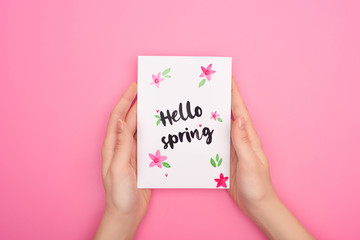 Cropped view of woman holding card with hello spring lettering on pink
