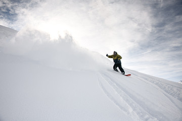 Naklejka na ściany i meble Freerider in anorak rides on a snowboard in mountains