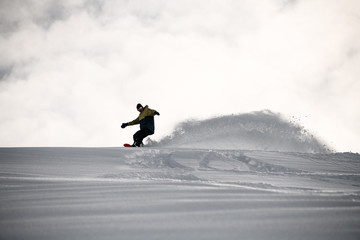 Freerider in full equipment sliding on a snowboard in mountains