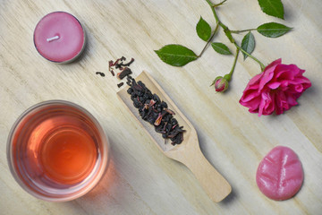 Flat lay of a cup of tea, loose tea, pink flower, tea light and a wax melt