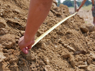 Hand of a man holding a measuring tape checking the length of land during a survey