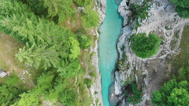 Top down view of narrow canyon with emerald crystal clear river, trees by river, rocky riverbeds, Great Soca Gorge in Trenta, Slovenia.