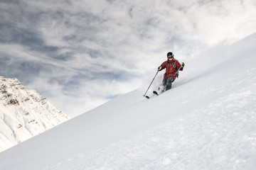 Smiling skiier slides down the mountain side