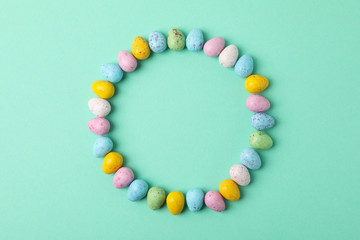 Circle made of multicolor Easter eggs on mint background, space for text